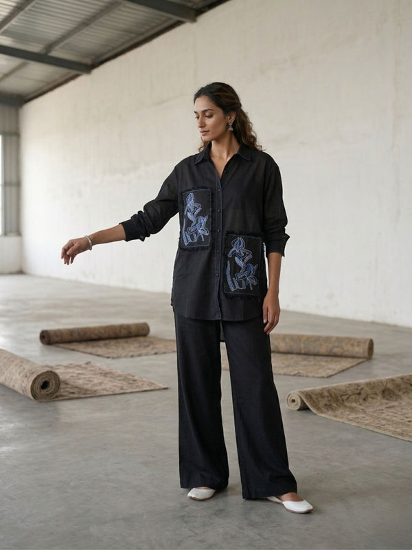 Women’s black button shirt and wide-leg pants set with blue embroidered patches, side pose