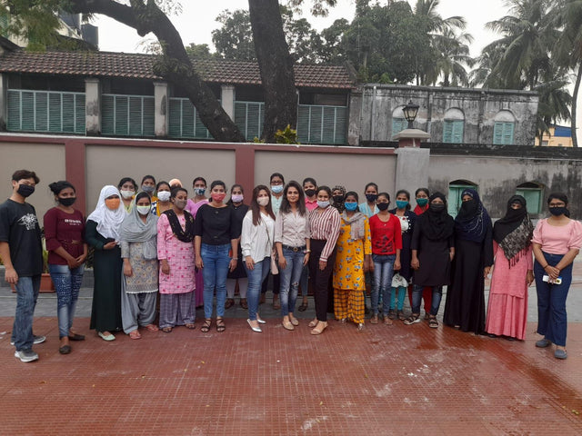 A diverse group of young adults posing for a group photo outdoors in casual attire.
